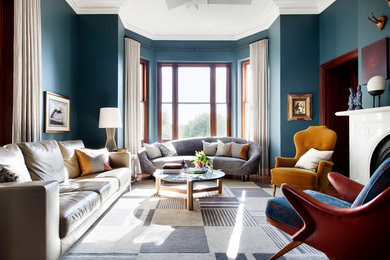 Réalisation d'un salon tradition fermé avec un mur bleu, un sol en bois brun, un manteau de cheminée en pierre, un sol marron, une salle de réception et une cheminée standard.