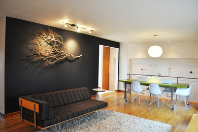 Example of a mid-century modern loft-style medium tone wood floor living room design in Portland with black walls
