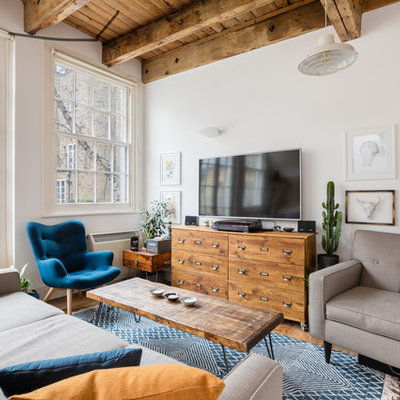 Inspiration for an industrial open concept medium tone wood floor and brown floor living room remodel in London with white walls and a wall-mounted tv