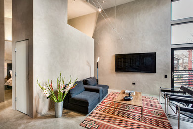 Foto de salón abierto urbano con paredes grises, televisor colgado en la pared y suelo gris