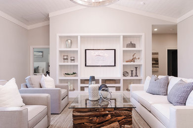 Modelo de salón abierto costero de tamaño medio con paredes blancas, suelo de madera clara y pared multimedia