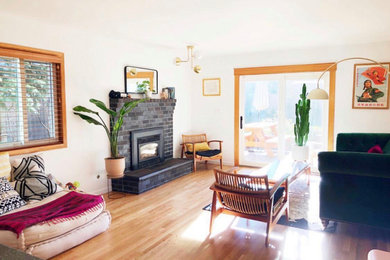 Example of a mid-sized cottage chic open concept light wood floor and brown floor living room design in Portland with white walls, a standard fireplace and a brick fireplace