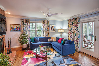 This is an example of a medium sized contemporary open plan living room in Baltimore with blue walls, medium hardwood flooring, a standard fireplace, a brick fireplace surround and a wall mounted tv.