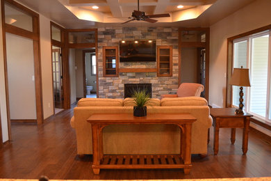 Imagen de salón abierto tradicional con paredes beige, suelo de madera en tonos medios, todas las chimeneas, marco de chimenea de piedra y televisor colgado en la pared