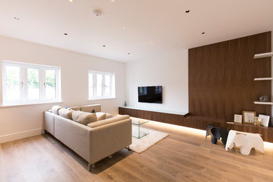 Imagen de salón para visitas cerrado contemporáneo de tamaño medio con paredes blancas, suelo de madera clara, televisor retractable y suelo marrón