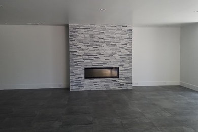 ロサンゼルスにある広いコンテンポラリースタイルのおしゃれなリビング (白い壁、横長型暖炉、石材の暖炉まわり、テレビなし、グレーの床) の写真