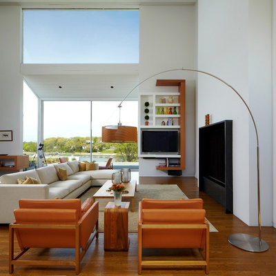 Example of a large minimalist medium tone wood floor living room design in New York with white walls, a standard fireplace and a media wall