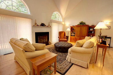 Cette photo montre un grand salon chic ouvert avec un mur blanc, parquet clair, une cheminée standard, un manteau de cheminée en plâtre et aucun téléviseur.