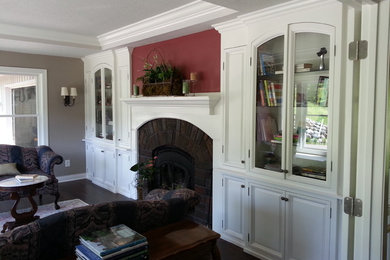 Example of a mid-sized arts and crafts dark wood floor living room library design in Minneapolis with red walls, a standard fireplace, a brick fireplace and no tv