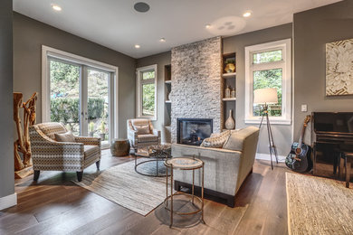 Mittelgroßes, Fernseherloses, Offenes Modernes Wohnzimmer mit grauer Wandfarbe, hellem Holzboden, Kamin, Kaminumrandung aus Stein und grauem Boden in Vancouver