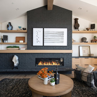 Fernseherloses, Offenes Maritimes Wohnzimmer mit weißer Wandfarbe, hellem Holzboden, Kamin, Kaminumrandung aus Backstein, freigelegten Dachbalken und Ziegelwänden in Orange County