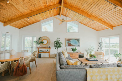 Mid-sized beach style open concept porcelain tile, beige floor and wood ceiling living room photo in Other with white walls and a wall-mounted tv