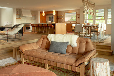 Imagen de salón abierto moderno grande sin televisor con paredes beige y suelo de madera clara