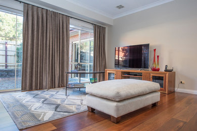 Offenes Modernes Wohnzimmer ohne Kamin mit weißer Wandfarbe, braunem Holzboden und freistehendem TV in Melbourne