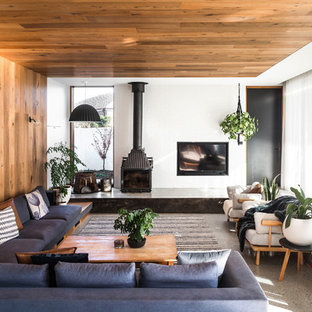 Large contemporary open concept living room in Hobart with white walls, concrete floors, a wood stove, grey floor, a concrete fireplace surround and a concealed tv.