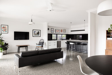 Cette image montre un grand salon minimaliste ouvert avec un mur blanc, sol en béton ciré, aucune cheminée, un téléviseur fixé au mur et un sol gris.