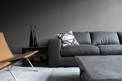 Foto de salón abierto actual con paredes grises, suelo de madera clara y televisor independiente