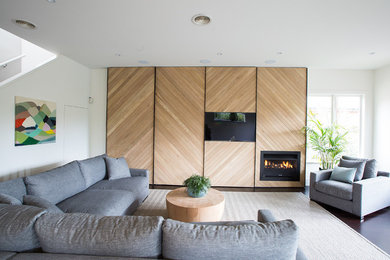 Idéer för vardagsrum, med vita väggar, mörkt trägolv, en inbyggd mediavägg och en bred öppen spis