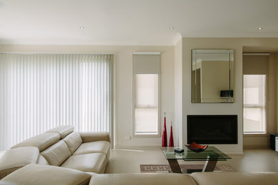 Immagine di un grande soggiorno minimalista aperto con pareti bianche, moquette, camino classico e cornice del camino in intonaco