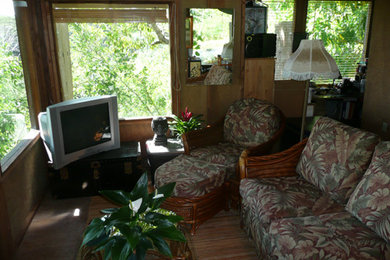 Foto de salón abierto tropical pequeño sin chimenea con paredes marrones, suelo de madera en tonos medios y televisor independiente