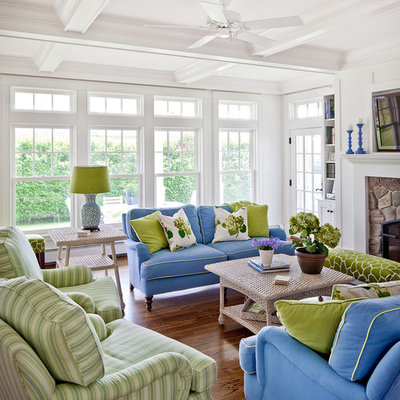 Example of a beach style enclosed medium tone wood floor and brown floor living room design in Portland Maine with white walls, a stone fireplace and a wall-mounted tv
