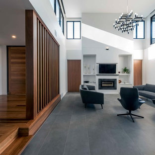 Design ideas for a contemporary open concept living room in Brisbane with white walls, ceramic floors, a standard fireplace, a tile fireplace surround, a wall-mounted tv and grey floor.