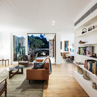 Ispirazione per un soggiorno design aperto con sala formale, pareti bianche, pavimento in legno massello medio, pavimento beige e TV a parete