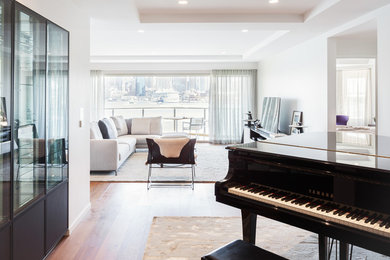 Medium sized modern open plan living room in Sydney with a music area, white walls, medium hardwood flooring, a freestanding tv and brown floors.