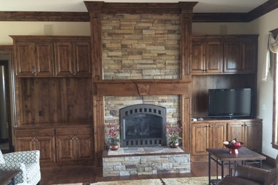 ウィチタにある中くらいなラスティックスタイルのおしゃれなLDK (白い壁、無垢フローリング、標準型暖炉、石材の暖炉まわり、据え置き型テレビ、茶色い床) の写真