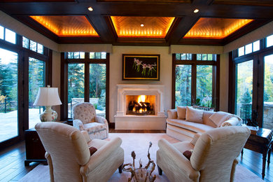 Example of a classic enclosed dark wood floor living room design in Denver with beige walls, a standard fireplace and a plaster fireplace