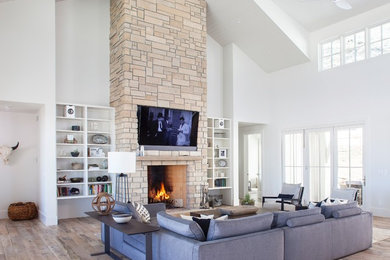 Inspiration for a cottage open concept medium tone wood floor and brown floor living room remodel in Denver with white walls, a standard fireplace, a stone fireplace and a wall-mounted tv
