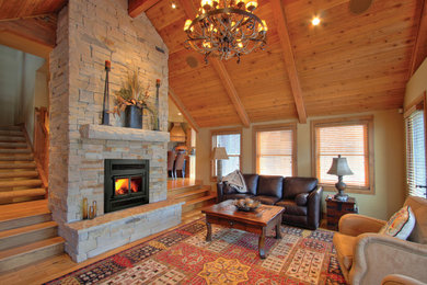 Inspiration for a large rustic formal and enclosed medium tone wood floor living room remodel in Minneapolis with green walls, a standard fireplace, a stone fireplace and no tv