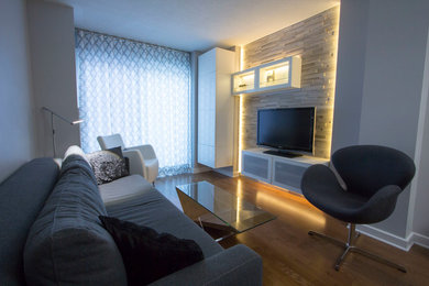 Aménagement d'un petit salon contemporain fermé avec un mur gris, un sol en bois brun et un téléviseur encastré.