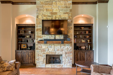 オースティンにある高級な中くらいなトラディショナルスタイルのおしゃれなリビング (ベージュの壁、コンクリートの床、標準型暖炉、石材の暖炉まわり、壁掛け型テレビ) の写真
