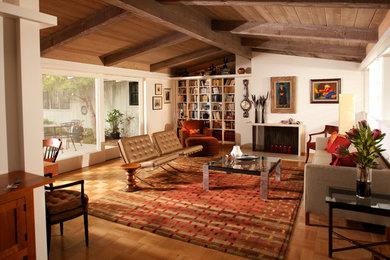 Modelo de salón bohemio con paredes beige y suelo de madera en tonos medios