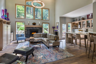Inspiration for a mid-sized transitional open concept medium tone wood floor and brown floor living room remodel in Other with gray walls, a standard fireplace, a stone fireplace and a media wall