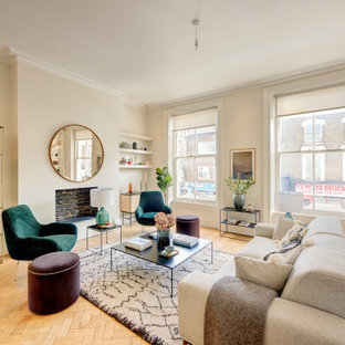 Classic formal open plan living room in London with white walls, medium hardwood flooring, a standard fireplace, a brick fireplace surround, no tv and brown floors.