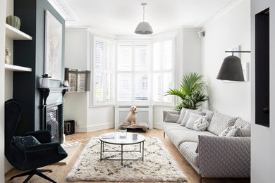 Photo of a medium sized scandi living room in London with white walls, light hardwood flooring, a standard fireplace, a metal fireplace surround, a wall mounted tv and brown floors.