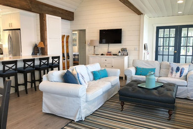 Example of a mid-sized beach style open concept laminate floor and gray floor living room design in Other with white walls, a wood stove, a tile fireplace and a wall-mounted tv