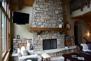 Large mountain style loft-style light wood floor living room photo in Minneapolis with beige walls, a standard fireplace, a stone fireplace and a wall-mounted tv