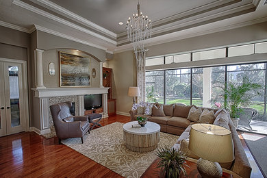 Mid-sized transitional open concept medium tone wood floor living room photo in Orlando with gray walls, a standard fireplace, a stone fireplace and a media wall