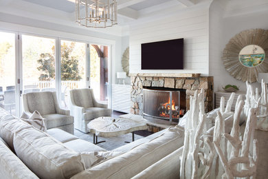 Example of a large beach style formal and enclosed dark wood floor and brown floor living room design in Charlotte with white walls, a standard fireplace, a stone fireplace and a wall-mounted tv