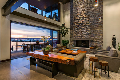 Example of a large trendy formal and open concept concrete floor and brown floor living room design in Seattle with a standard fireplace, a stone fireplace, beige walls and no tv