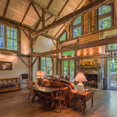 Mountain style open concept medium tone wood floor living room photo in Other with beige walls, a standard fireplace and a stone fireplace