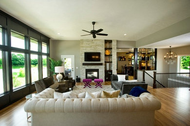 Trendy open concept medium tone wood floor living room photo in Omaha with a two-sided fireplace