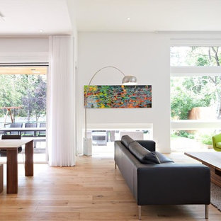 Mittelgroßes, Repräsentatives, Abgetrenntes Modernes Wohnzimmer mit weißer Wandfarbe, hellem Holzboden, Tunnelkamin, verputzter Kaminumrandung, Wand-TV und beigem Boden in Calgary