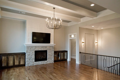 Large transitional open concept medium tone wood floor and brown floor living room photo in Kansas City with beige walls, a standard fireplace, a stone fireplace and a wall-mounted tv