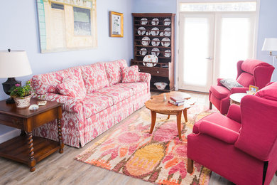 Modelo de salón cerrado bohemio pequeño con paredes azules, suelo de madera clara, televisor colgado en la pared y chimeneas suspendidas