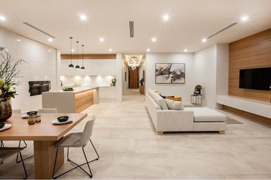 Modelo de salón para visitas abierto moderno grande con paredes blancas, suelo de baldosas de porcelana y televisor colgado en la pared