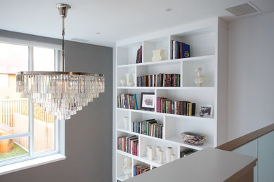 Пример оригинального дизайна: открытая гостиная комната среднего размера в современном стиле с с книжными шкафами и полками и белыми стенами